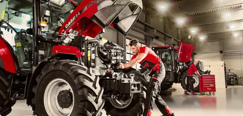 Mechanic working on tractor engine in well-equipped service center